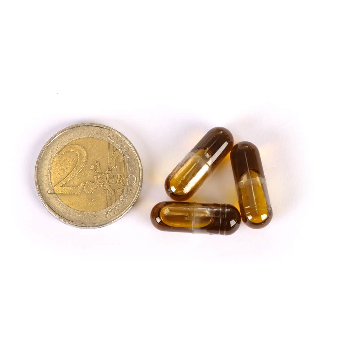 Trois capsules Medihemp CBD 5 % (25 mg) à côté d'une pièce en euro sur fond blanc.